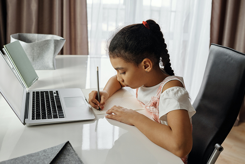 Young Hispanic girl studying typing at her desk.